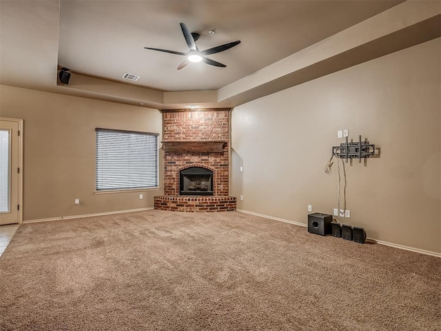 unfurnished living room with a fireplace, a raised ceiling, ceiling fan, and carpet