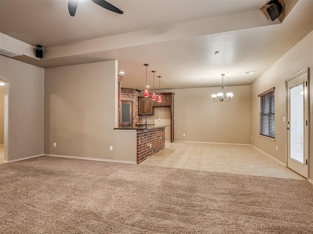 unfurnished living room with ceiling fan with notable chandelier, light colored carpet, and sink