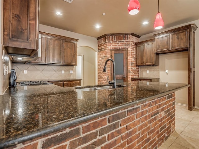 kitchen with sink, pendant lighting, light tile patterned floors, and dark stone counters