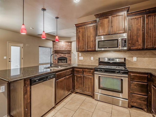 kitchen with sink, decorative light fixtures, stainless steel appliances, a fireplace, and backsplash