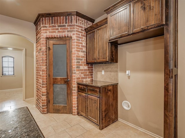 kitchen featuring dark stone countertops, backsplash, and light tile patterned flooring