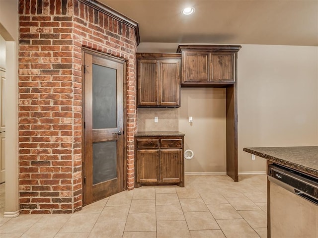 kitchen featuring tasteful backsplash, stainless steel dishwasher, dark brown cabinetry, and light tile patterned floors