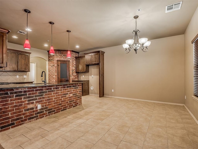 kitchen with pendant lighting, light tile patterned floors, decorative backsplash, and a notable chandelier