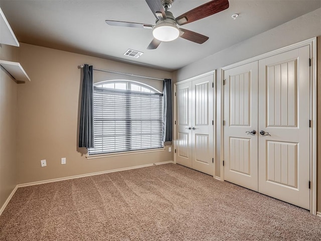 unfurnished bedroom featuring carpet floors, two closets, and ceiling fan