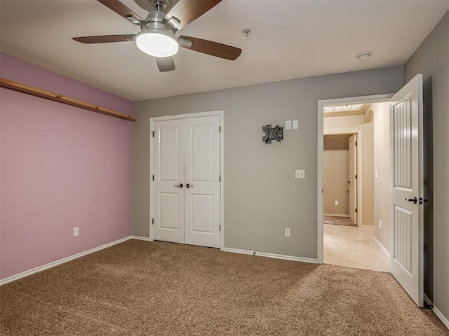 unfurnished bedroom with ceiling fan, a closet, and light carpet