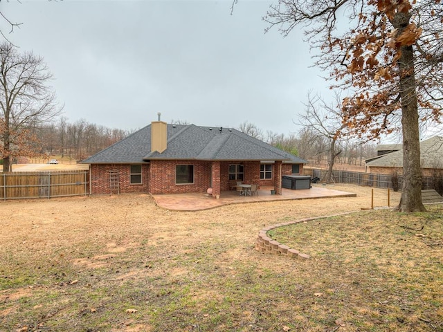 rear view of house with a yard, a jacuzzi, and a patio