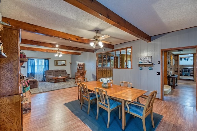 dining area featuring hardwood / wood-style flooring, ceiling fan, beam ceiling, and a textured ceiling