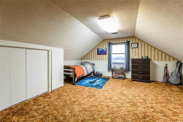 bedroom with carpet floors, a closet, a textured ceiling, and vaulted ceiling