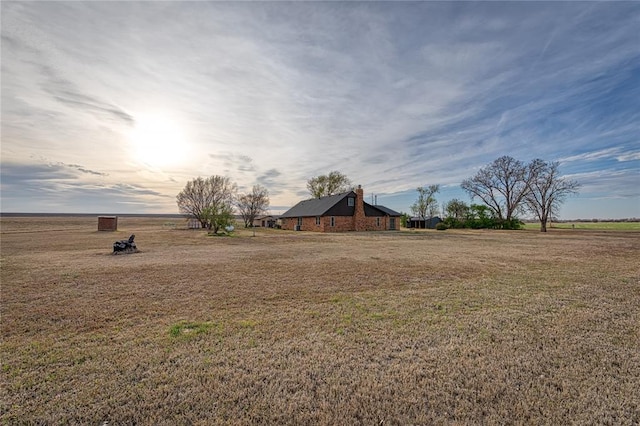 yard at dusk featuring a rural view