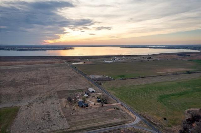 aerial view at dusk with a water view and a rural view