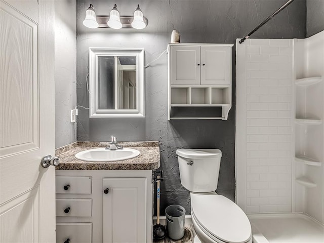 bathroom with vanity, a shower, and toilet