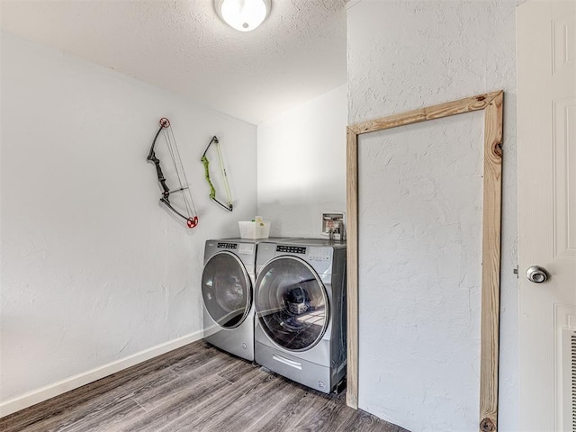 clothes washing area with hardwood / wood-style flooring, washing machine and clothes dryer, and a textured ceiling