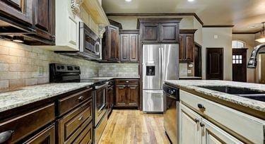 kitchen featuring appliances with stainless steel finishes, sink, decorative backsplash, light hardwood / wood-style floors, and crown molding