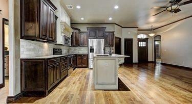 kitchen with decorative backsplash, stainless steel appliances, light hardwood / wood-style floors, and a center island with sink