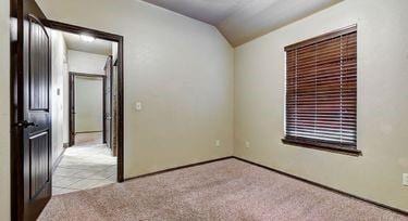 carpeted spare room featuring vaulted ceiling