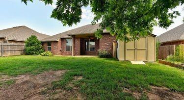 rear view of property featuring a storage shed and a lawn