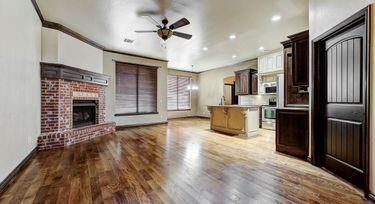 kitchen with wood-type flooring, dark brown cabinets, ornamental molding, ceiling fan, and a fireplace