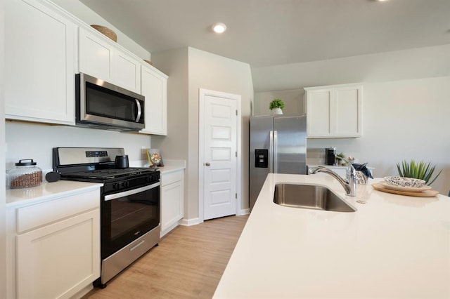 kitchen featuring appliances with stainless steel finishes, light countertops, light wood-style floors, white cabinetry, and a sink