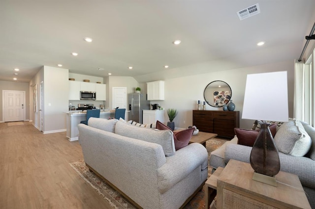 living area with baseboards, light wood-style flooring, visible vents, and recessed lighting