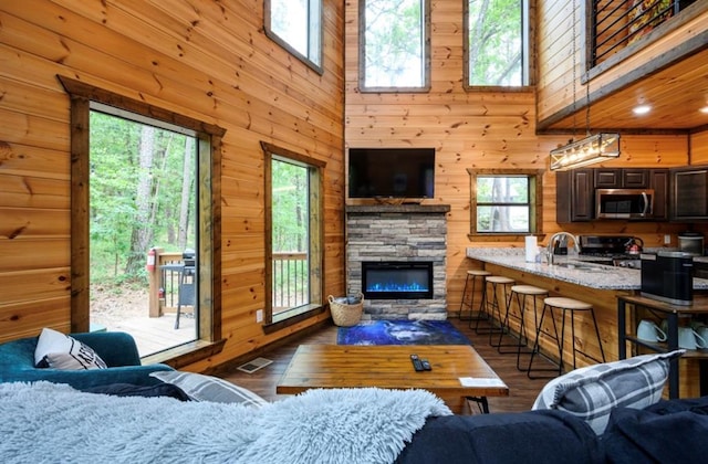 living room featuring a fireplace, dark wood finished floors, visible vents, and wooden walls