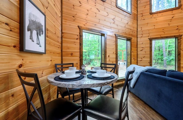 dining space featuring wood walls, a high ceiling, and wood finished floors