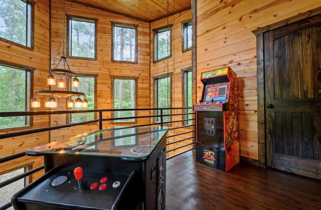 playroom featuring dark wood finished floors, wooden ceiling, wood walls, and a high ceiling