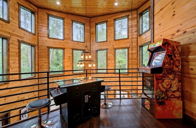 rec room with wood ceiling, wooden walls, a high ceiling, and wood finished floors