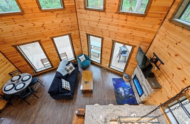 living room with a skylight, wood walls, a towering ceiling, and wood finished floors