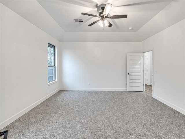 carpeted spare room featuring ceiling fan and a tray ceiling