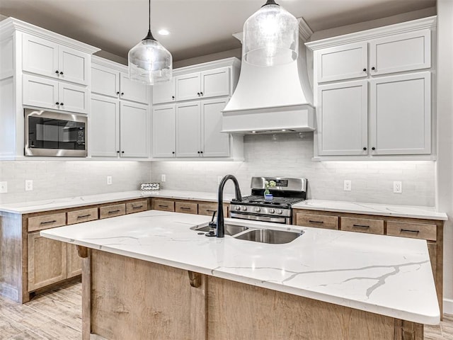 kitchen with built in microwave, an island with sink, and white cabinets