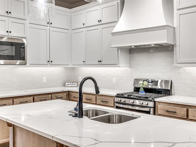 kitchen with built in microwave, custom exhaust hood, gas range, light stone counters, and white cabinets