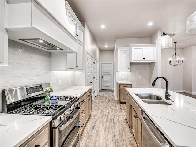 kitchen featuring sink, custom exhaust hood, white cabinetry, appliances with stainless steel finishes, and light stone countertops