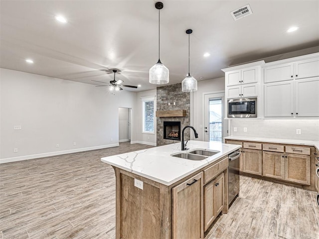 kitchen featuring sink, white cabinetry, a center island with sink, built in microwave, and stainless steel dishwasher