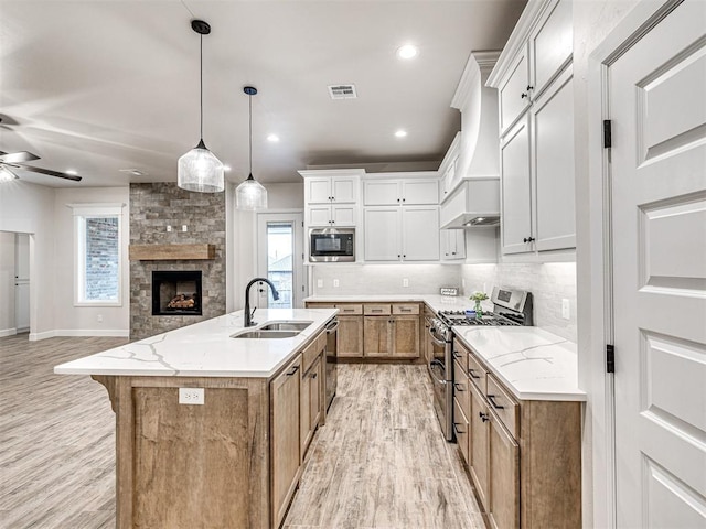 kitchen featuring sink, white cabinetry, light stone counters, stainless steel appliances, and a kitchen island with sink