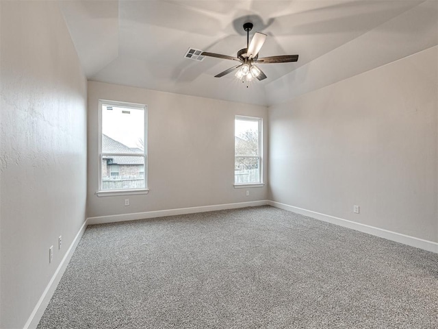 empty room with carpet, ceiling fan, and a tray ceiling