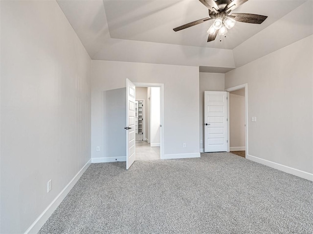 unfurnished bedroom featuring light carpet, a raised ceiling, and ceiling fan