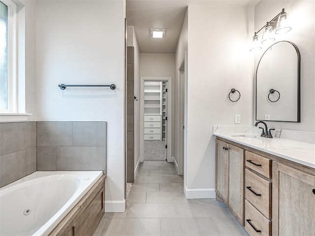 bathroom with tile patterned flooring, vanity, and tiled bath