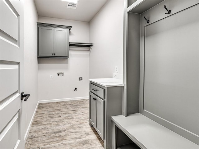 laundry area featuring washer hookup, light hardwood / wood-style floors, and cabinets