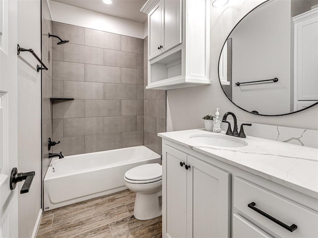 full bathroom with wood-type flooring, toilet, tiled shower / bath combo, and vanity