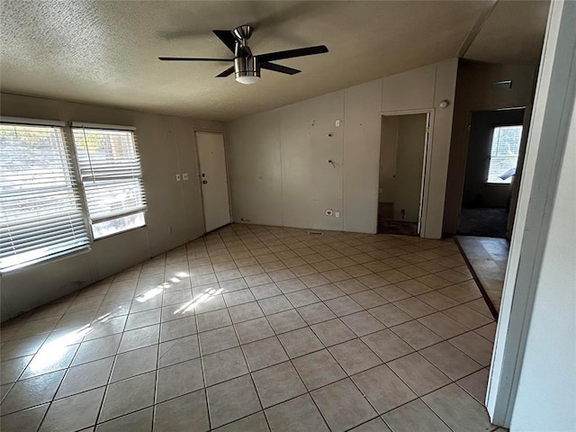 tiled empty room featuring vaulted ceiling, a textured ceiling, and ceiling fan