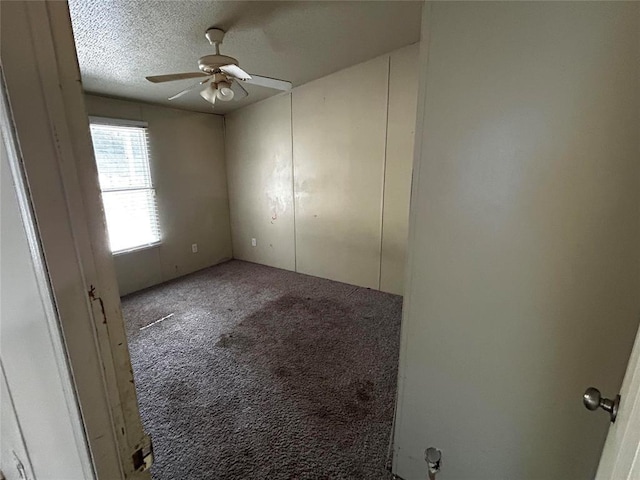 carpeted empty room featuring ceiling fan and a textured ceiling