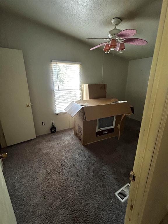 bedroom with dark carpet, vaulted ceiling, and a textured ceiling