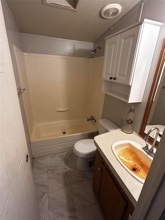 full bathroom featuring vanity, toilet, shower / bath combination, and a textured ceiling