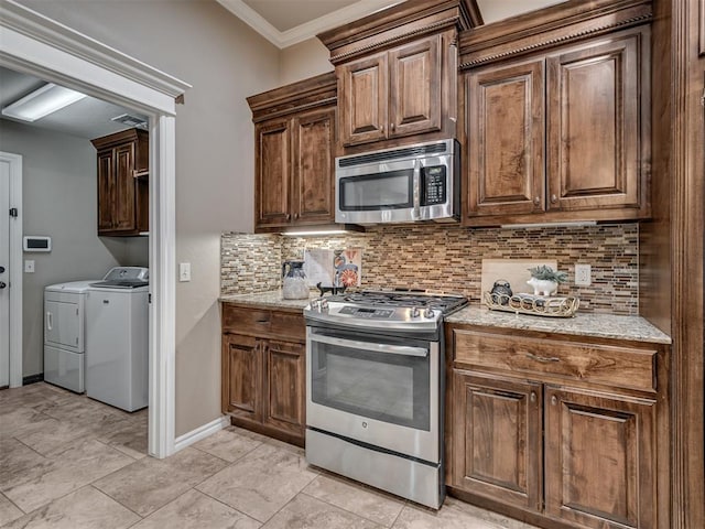 kitchen with stainless steel appliances, washer and dryer, light stone counters, and decorative backsplash