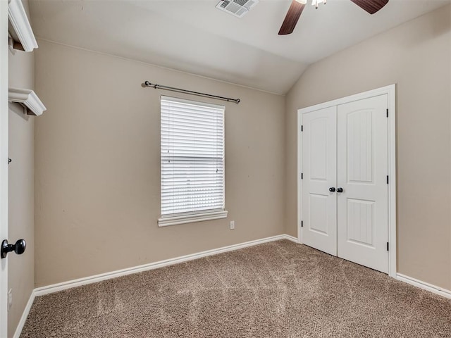 unfurnished bedroom with vaulted ceiling, a closet, ceiling fan, and carpet flooring