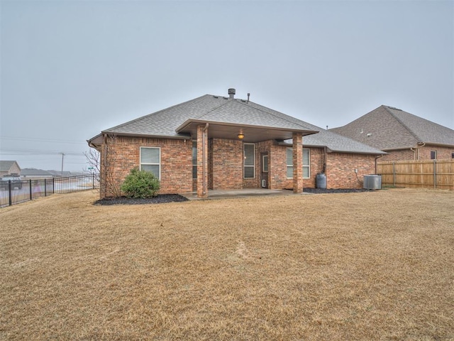 back of property featuring central AC unit, a patio area, and a lawn