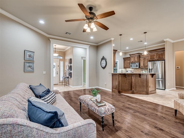 living room featuring light hardwood / wood-style flooring, ornamental molding, and ceiling fan