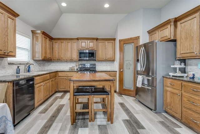 kitchen featuring vaulted ceiling, a kitchen island, appliances with stainless steel finishes, sink, and decorative backsplash