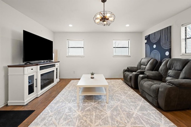 living room with an inviting chandelier, plenty of natural light, and hardwood / wood-style floors