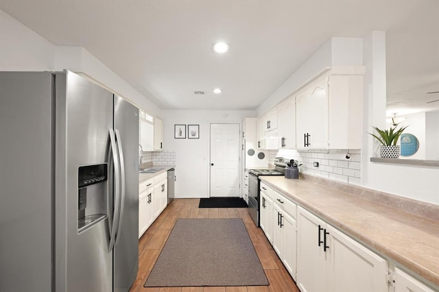 kitchen featuring tasteful backsplash, sink, stainless steel appliances, and white cabinets